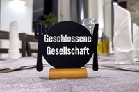 Schild mit der Aufschrift 'Geschlossene Gesellschaft' auf einem gedeckten Tisch in einem Restaurant.