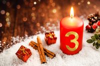 Rote Kerze mit der Zahl 3, umgeben von Zimtstangen und Geschenken im Schnee als Adventsgruß zum 3. Advent.