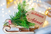 Schlitten mit Tannenzweigen und Karte mit der Aufschrift 'Schönen Advent' für schöne Adventszeit Grüße