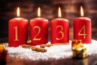 Advent 2024: Vier brennende rote Adventskerzen mit den Zahlen 1 bis 4, dekoriert mit Zimtstangen und Schneeflocken.