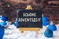 Schiefertafel mit der Aufschrift schöne Adventszeit im Schnee, umgeben von blauen Weihnachtskugeln und Sternen.