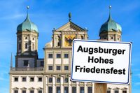 Augsburger Hohes Friedensfest, steht auf einem Schild, vor dem historischen Rathaus in Augsburg – Symbol des Feiertags.