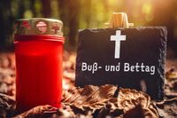 Buß- und Bettag Symbol: Eine rote Gedenkkerze und eine Schiefertafel mit Kreuz, symbolisch für den evangelischen Feiertag, umgeb