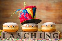 Drei Faschingskrapfen stehen auf Würfel mit Schriftzug Fasching.