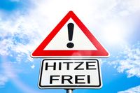 Schild mit einem Ausrufezeichen und der Aufschrift ‚Hitzefrei‘ unter einem strahlend blauen Himmel.