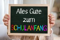 Kind hält eine Tafel mit der Aufschrift ‚Alles Gute zum Schulanfang‘, passend zum Schulstart 2025.