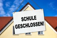 Schild mit der Aufschrift ‚Schule geschlossen!‘ vor einem Gebäude, passend zur Schulschließung und Unterrichtsausfall.