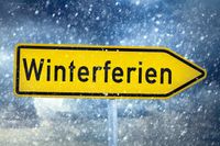 Gelbes Schild mit der Schriftzug ‚Winterferien‘, umgeben von Schneefall, passend zu den Winterferien 2025.