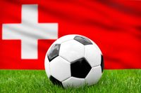 Fußball vor der Schweiz-Fahne, symbolisierend die schweizerische Nationalmannschaft und den Fußball.