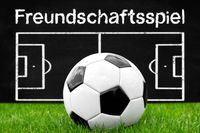 Fußball Freundschaftsspiel auf dem Spielfeld mit taktischer Darstellung im Hintergrund.