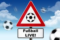 Ein Verkehrsschild mit einem Fußball-Symbol und der Aufschrift 'Fußball LIVE!' vor blauem Himmel mit Wolken.