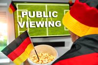 Ein Fan mit Deutschland-Flagge schaut auf einen Bildschirm mit der Aufschrift 'Public Viewing', bereit für ein Fußballspiel.