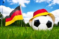 Fußball mit Deutschlandflagge und Hut in Schwarz-Rot-Gold auf einem Spielfeld, symbolisch für ein Deutschland-Spiel im Fußball.