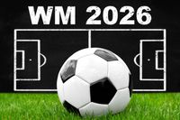 Ein Fußball auf einem Spielfeld vor einer Tafel mit der Aufschrift 'WM 2026', symbolisch für die Fußball-Weltmeisterschaft 2026.