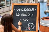 Geschlossen-Schild mit der Aufschrift ‚Wir sind bald zurück!‘, handgeschrieben auf einer Tafel.