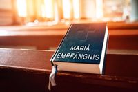 Mariä Empfängnis steht auf einer Bibel in einer Kirche. Symbolisiert den Mariä Empfängnis Feiertag in Österreich.