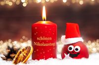 Lustiger Nikolausgru, Weihnachtskugel mit Gesicht, neben Kerze und Aufschrift: Schönen Nikolaustag.