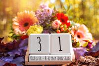 Kalender mit dem Datum 31. Oktober – Reformationstag, umgeben von bunten Blumen – Symbol für den Reformationstag Feiertag.