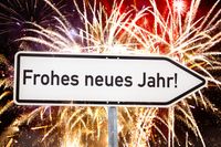 Neujahrsgrüße Frohes Neues Jahr mit Straßenschild und Feuerwerk im Hintergrund.