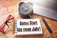 Spruch neue Jahr kurz, Papier mit der Aufschrift „Guten Start ins neue Jahr“ liegt neben einem Wecker.