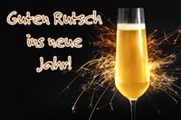 Guten Rutsch ins neue Jahr. Ein Glas Sekt vor schwarzem Hintergrund mit Wunderkerzen zum Jahreswechsel.