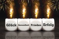 Wünsche zum neuen Jahr. Vier Würfel mit den Worten Glück, Gesundheit, Frieden, Erfolg, darüber Feuerwerk.