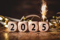 Frohes Neues Jahr 2025 mit Holzblöcken und Wunderkerze als Silvesterdekoration.