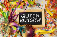 Silvesterbilder mit Guten Rutsch-Tafel, Maske und bunten Luftschlangen.