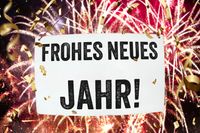 Bilder zu Neujahr mit Frohes Neues Jahr-Schild und Feuerwerk im Hintergrund.