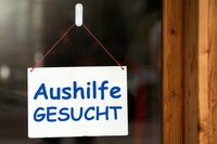 Aushilfe gesucht – Schild an einer Ladentür weist darauf hin, dass eine Aushilfe gesucht wird. Bild für Stellenangebot.