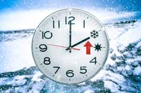 Eine Uhr zeigt das Uhren umstellen auf Winterzeit an, vor einem verschneiten Hintergrund – Symbol für die Umstellung der Uhren zur Winterzeit.