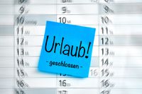 Geschlossen wegen Urlaub: Blaues Post-it auf Kalender mit handschriftlichem Text 'Urlaub! - geschlossen -'. Perfekt für Urlaubsbilder und Mitteilung über geschlossene Geschäfte während des Urlaubs.