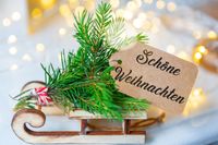 Schöne Weihnachtsbilder: Etikett auf Holzschlitten mit Tannenzweigen und Lichtern.