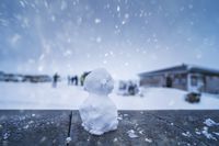 Klassisches Bild vom Schneemann, ein kleiner Schneemann sitzt auf einer Bank im Schnee.