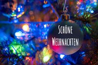 Bild zu Weihnachten: Eine bunte Christbaumkugel mit der Aufschrift ‚Schöne Weihnachten‘ hängt am Baum.