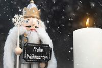 Nussknacker mit Schild und Kerze im Schnee, ein klassisches Motiv für frohe Weihnachten Bilder.