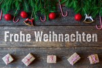 Bild frohe Weihnachten Schriftzug mit Tannenzweigen und Geschenken.