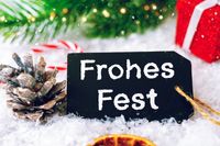 Eine Tafel mit frohes Fest Schriftzug, umgeben von Weihnachtsdeko, ideal für Grüße zu Weihnachten.