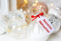 Besinnliche Weihnachtswünsche mit Christbaumkugeln und rotem Geschenkanhänger.