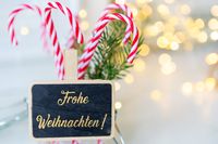 Besinnliche Weihnachtswünsche auf einer Tafel, umgeben von Zuckerstangen und festlicher Dekoration.