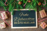 Wünsche zum Weihnachtsfest mit festlicher Dekoration, Tafel und Geschenken.