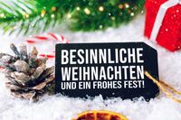 Wünsche zum Weihnachtsfest mit Tannenzapfen, Weihnachtsbaumzweig und festlichen Dekorationen.