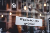 eihnachten geöffnet – Schild an einem Fenster mit Schneeflocken und Lichtern.