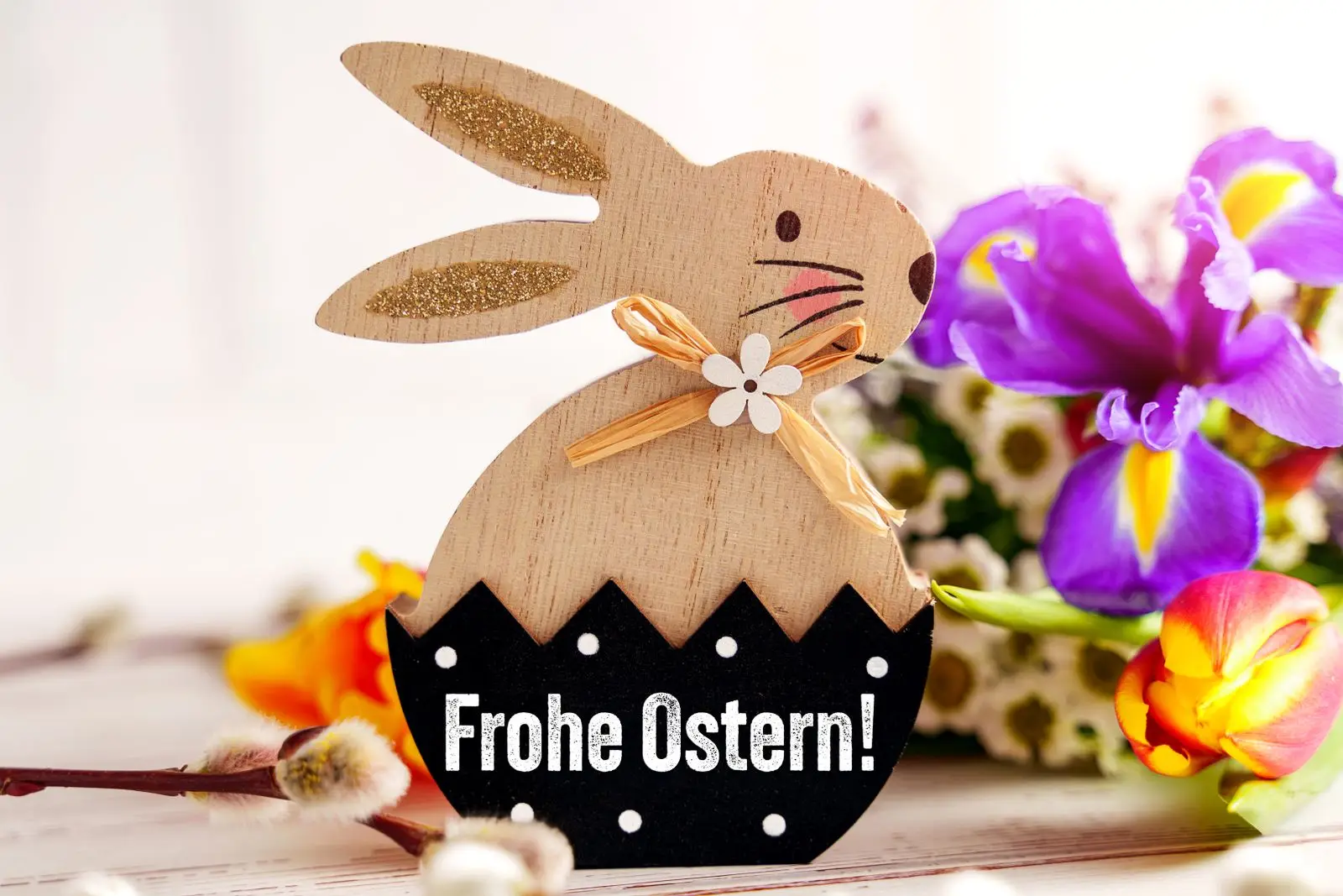 Ostergruß frohe ostern schriftzug auf osterhase neben blumen