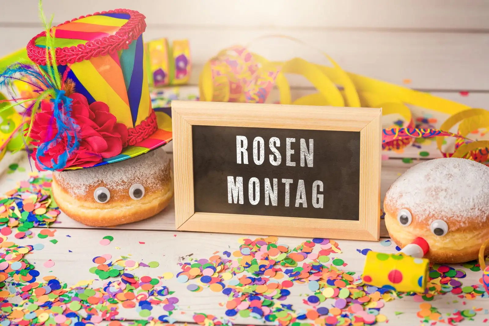 Rosenmontag steht auf einem schild neben faschingsdeko und krapfen