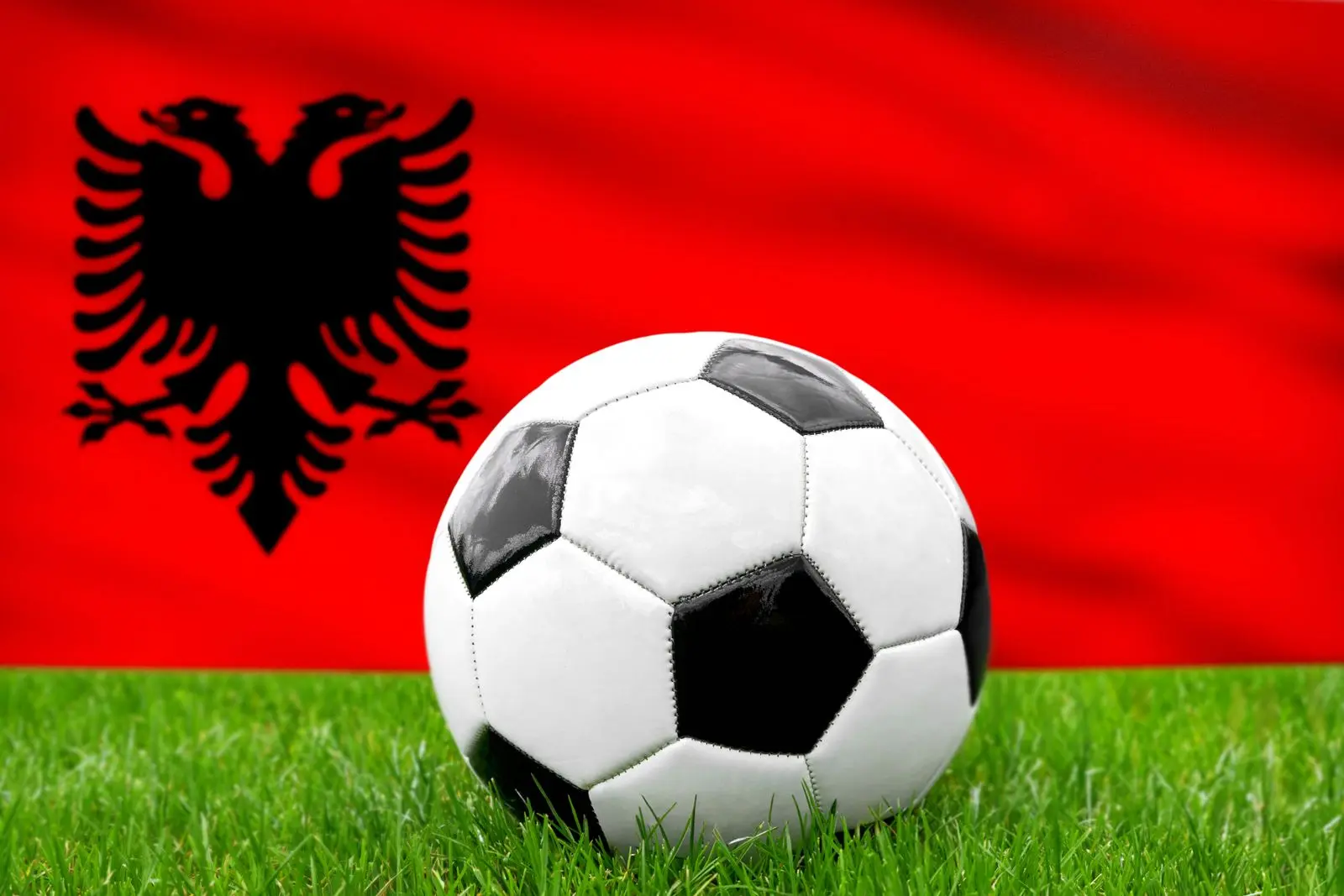 Ein fußball vor der albanischen fahne repräsentiert die nationalmannschaft von albanien im fußball.