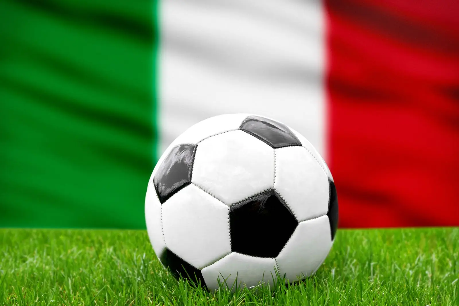 Ein fußball vor der italienischen fahne symbolisiert die nationalmannschaft von italien im fußball.