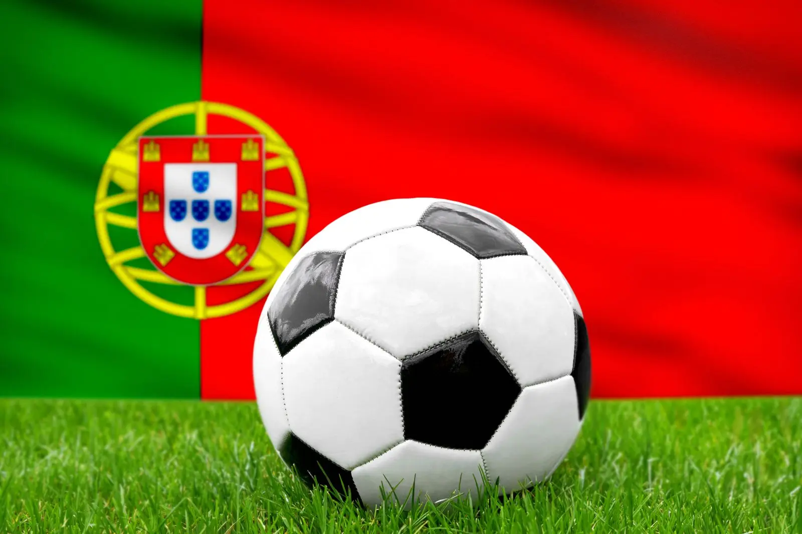Ein fusball vor der portugiesischen fahne reprasentiert die nationalmannschaft von portugal im fusball
