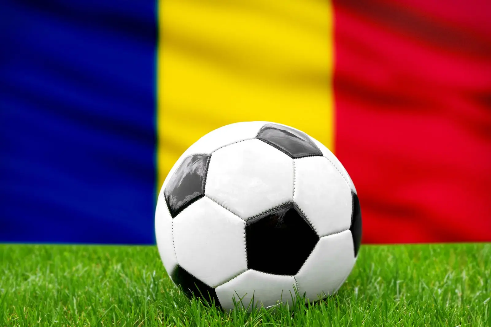 Ein fußball vor der rumänischen fahne steht symbolisch für die nationalmannschaft von rumänien im fußball.