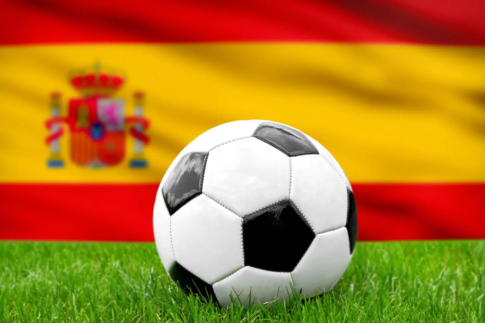Ein fusball vor der spanischen fahne symbolisiert die nationalmannschaft von spanien im fusball